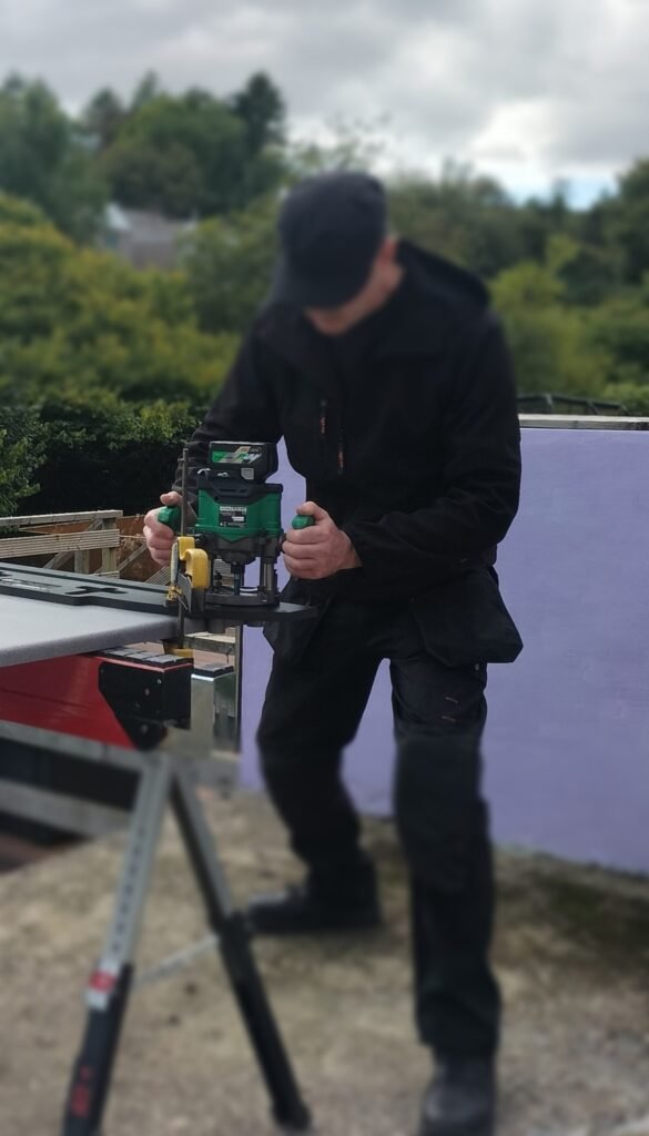 A carpenter using the Hikoki brushless multivolt router M3612DA in conjunction with a Trend worktop Jig