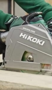 A HiKOKI power tool operator demonstrates the cutting motion of the C3606DPA cordless plunge saw. The picture is close-in on the saw itself and the user is wearing a distinctive HiKOKI dark green top and protective gloves.