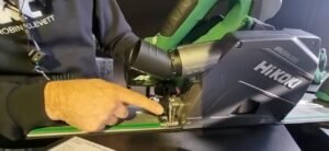Robin Clevett inspects the HiKOKI Plunge Saw at an exhibition. The photo shows him pointing at the unique bevel adjustment mechanism